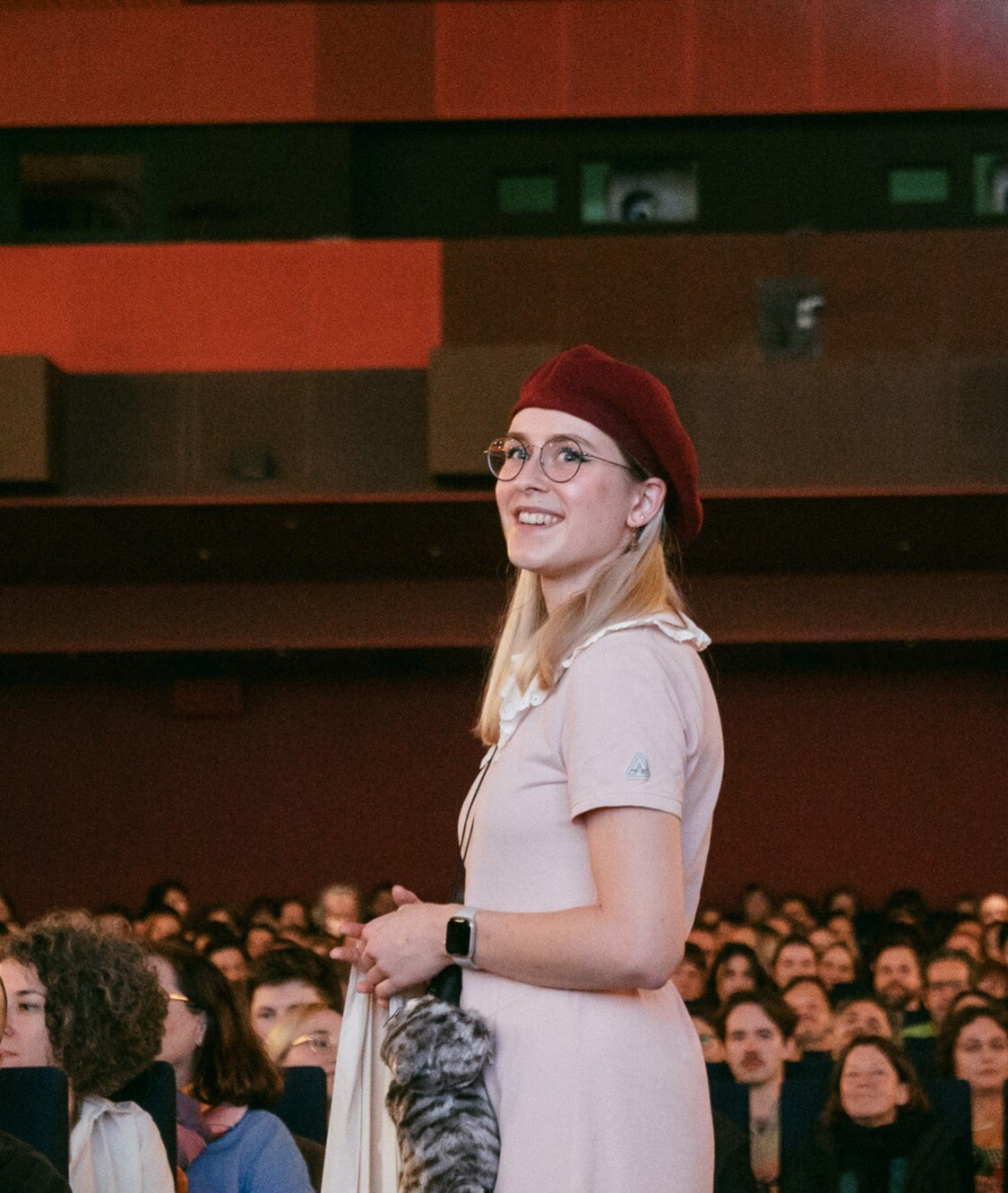 Frau mit rosa Kleid und rotem Hut im Kinogang